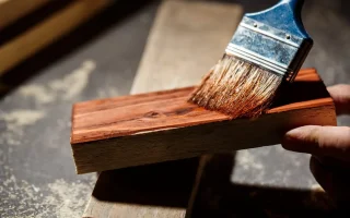 Imagem de uma pessoa aplicando resina epóxi em uma madeira, ideal para quem procura onde comprar resina epóxi para madeira. A resina proporciona acabamento e proteção.