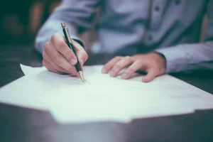 Pessoa assinando documento relacionado à rescisão de contrato de aluguel, ilustrando o processo de encerramento de um contrato de locação.