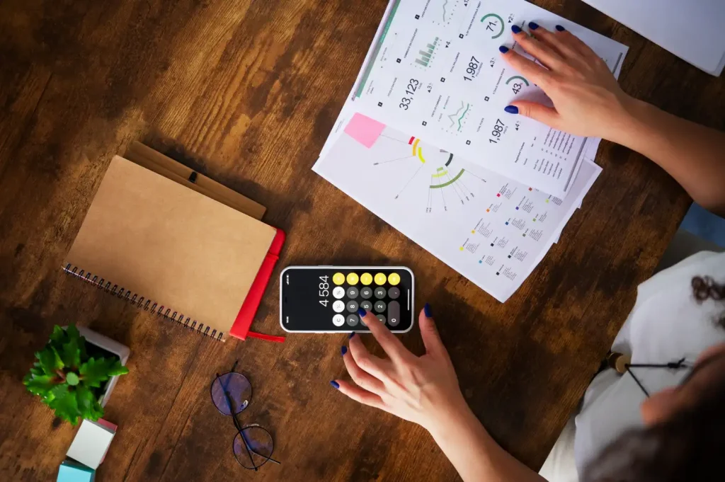 Pessoa analisando relatórios financeiros e números em um aplicativo de calculadora para criar relatórios eficientes que facilitam decisões estratégicas.