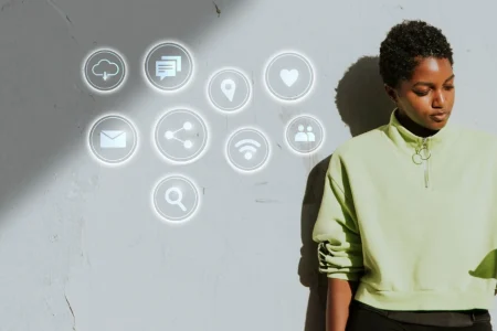 Jovem mulher utilizando smartphone com ícones de tecnologia e marketing digital flutuando ao seu redor, simbolizando dicas para acompanhar as tendências de marketing digital em 2025.