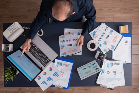 Imagem de um escritório com documentos, tablet, computador portátil e telefone, focada em gestão financeira de pequenas indústrias, abordando contas a pagar e receber.