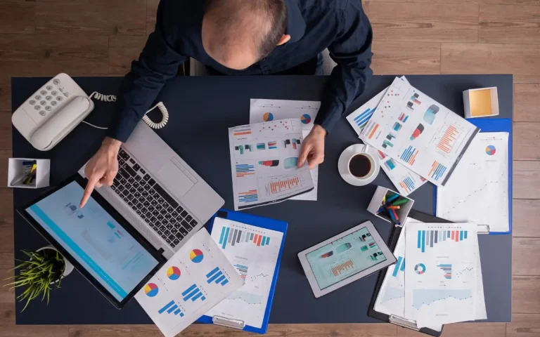 Imagem de um escritório com documentos, tablet, computador portátil e telefone, focada em gestão financeira de pequenas indústrias, abordando contas a pagar e receber.