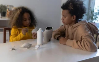 Crianças criando pinturas em objetos de porcelana como parte de uma atividade de artesanato, ilustrando criatividade na transformação de móveis antigos com pintura.