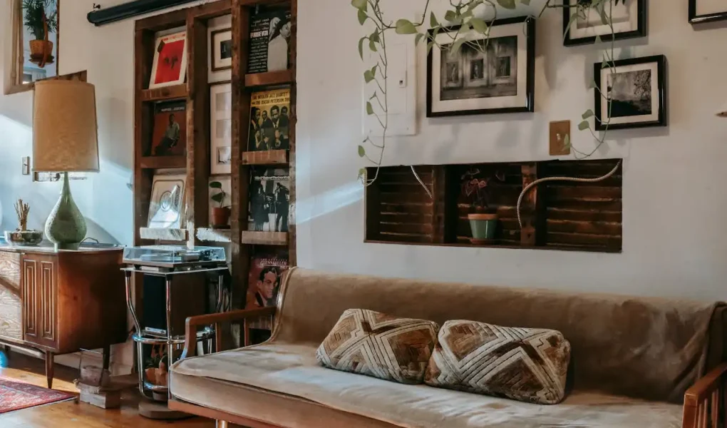 Imagem de sala de estar decorada com ideias de decoração faça você mesmo com materiais reciclados, incluindo prateleiras de madeira, quadros e plantas.