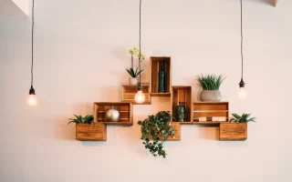 Decoração com móveis multifuncionais em parede com caixas de madeira, plantas e iluminação pendurada, ideal para ambientes compactos e bem aproveitados.