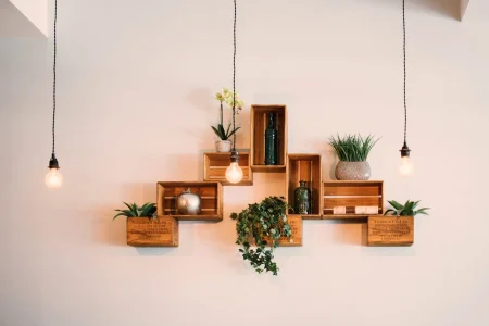 Decoração com móveis multifuncionais em parede com caixas de madeira, plantas e iluminação pendurada, ideal para ambientes compactos e bem aproveitados.