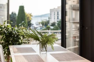Imagem de uma varanda bem decorada com uma mesa de jantar, vaso de plantas verdes e vista para a cidade, ideal para dicas de aproveitamento de varandas e cantinhos da casa.