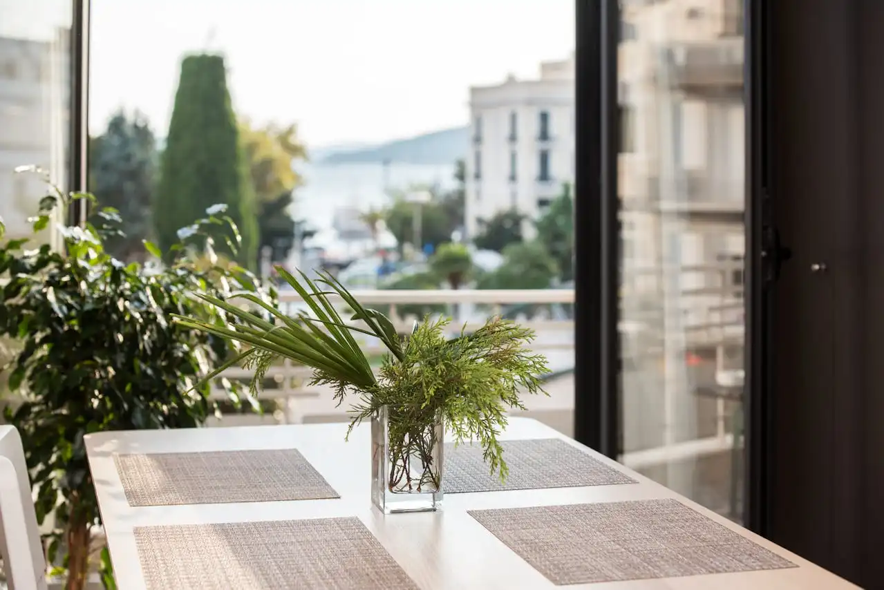 Imagem de uma varanda bem decorada com uma mesa de jantar, vaso de plantas verdes e vista para a cidade, ideal para dicas de aproveitamento de varandas e cantinhos da casa.
